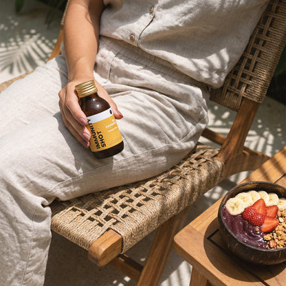Person drinking Bali Rain Immunity Shot outdoors, healthy wellness shot on the go Bali