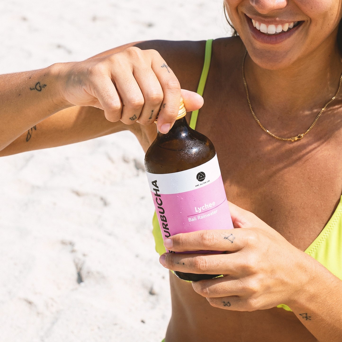 Woman drinking Bali Rain Sourbucha™ Lychee outdoors, healthy gut drink on the go Bali